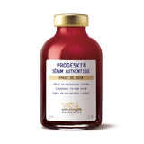 A vial of Biologique Recherche Progeskin Serum with a white label, red liquid visible inside, and a gold-colored cap.